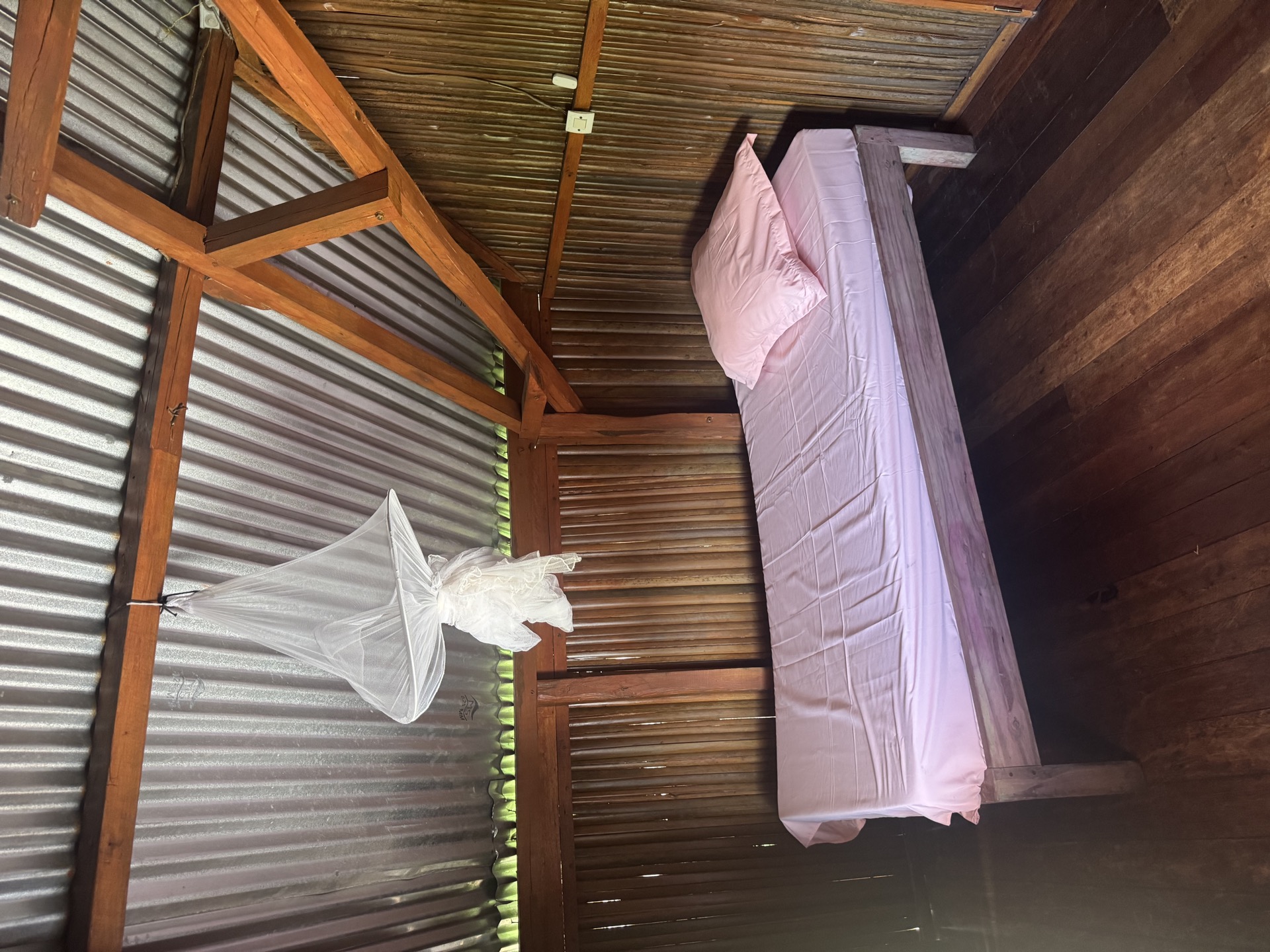 Chambre simple en bois avec moustiquaire